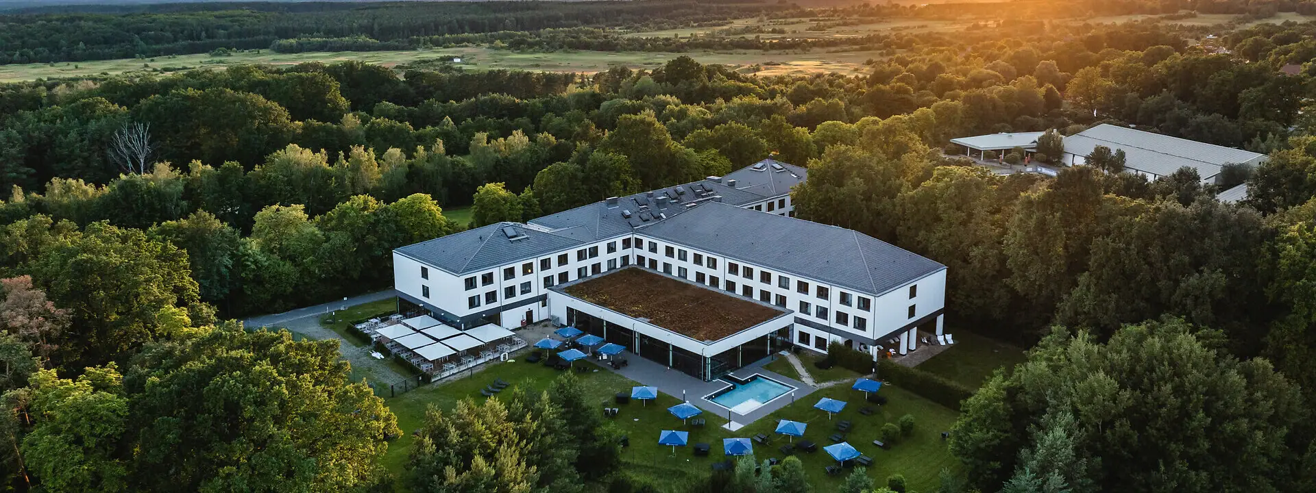aja Bad Saarow Ein Gebäude mit einem Pool, umgeben von Bäumen.