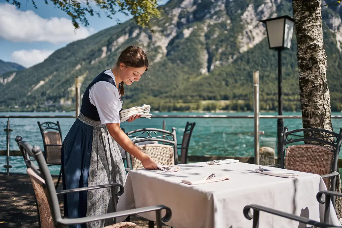 Eine Frau arbeitet im Gastgarten vom aja Fürstenhaus am Achensee mit dem See im Hintergrund.