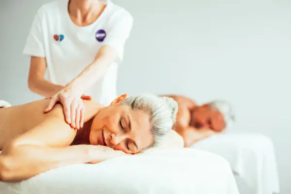 Paarmassage Eine Frau und ein Mann liegen auf einem Bett.