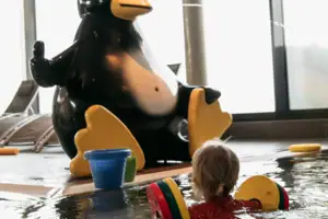 Ein Kind schwimmt in einem Pool neben einer Pinguin-Statue.