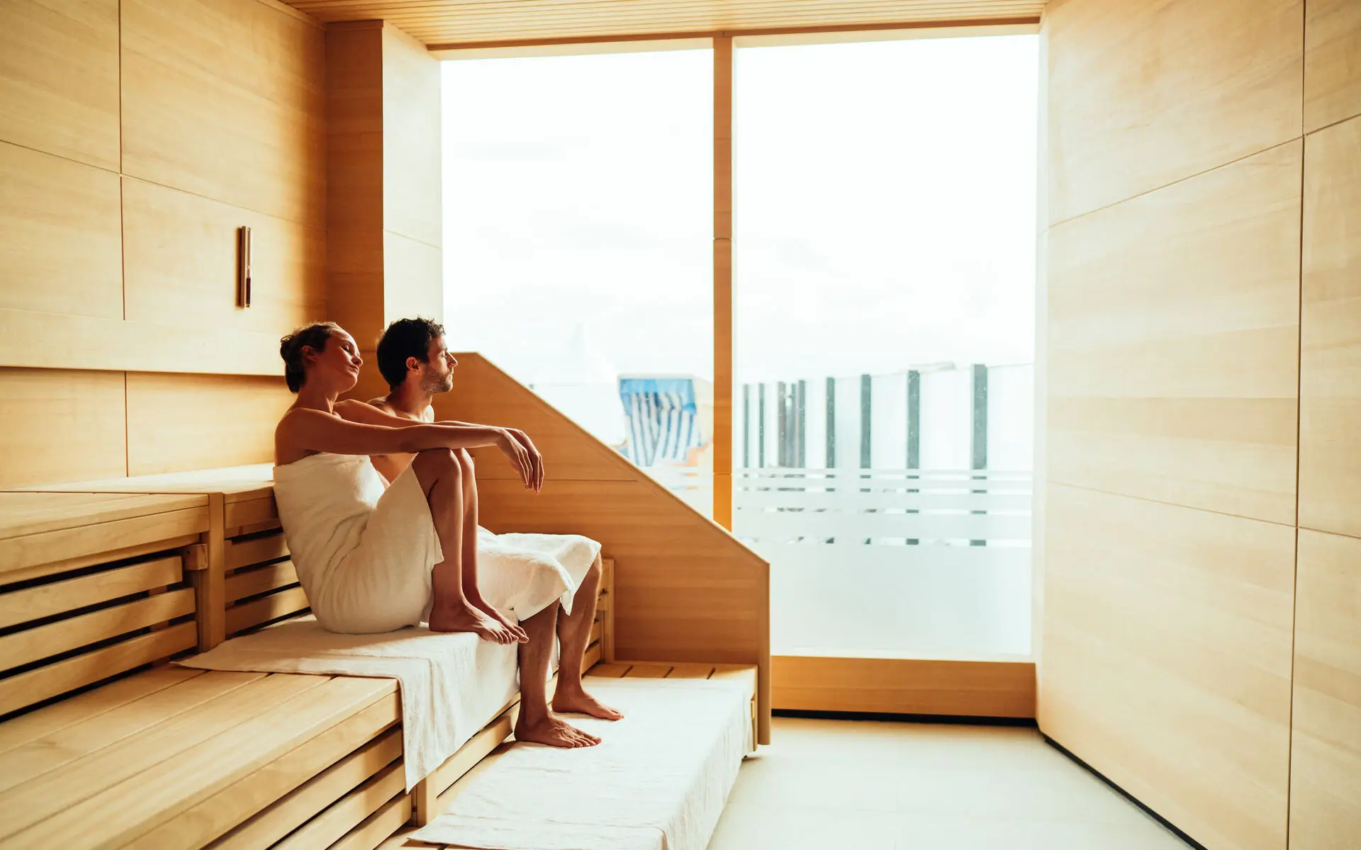 Ein Mann und eine Frau sitzen in einer Sauna auf einer Bank.