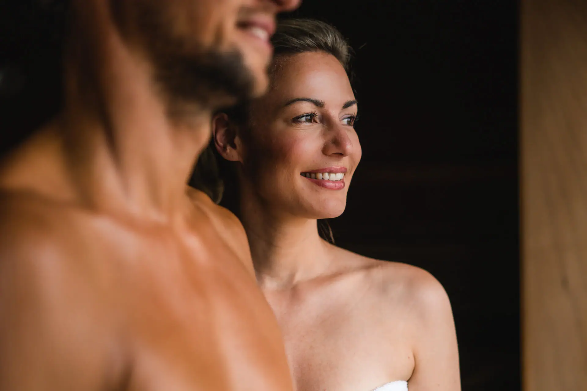 Ein Mann und eine Frau lächeln und stehen in einer Sauna.