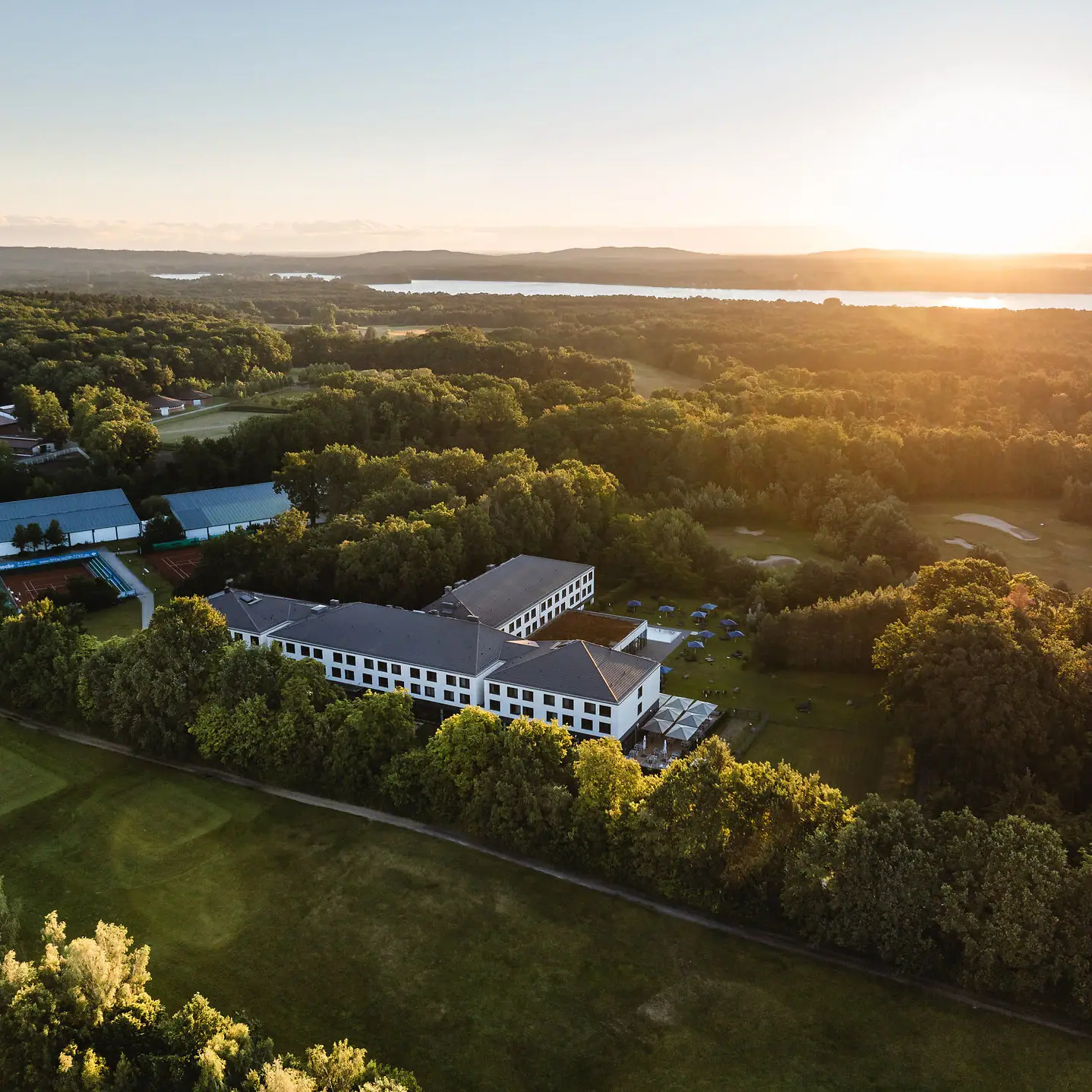 aja Bad Saarow Ein Gebäude umgeben von Bäumen und einem Gewässer.