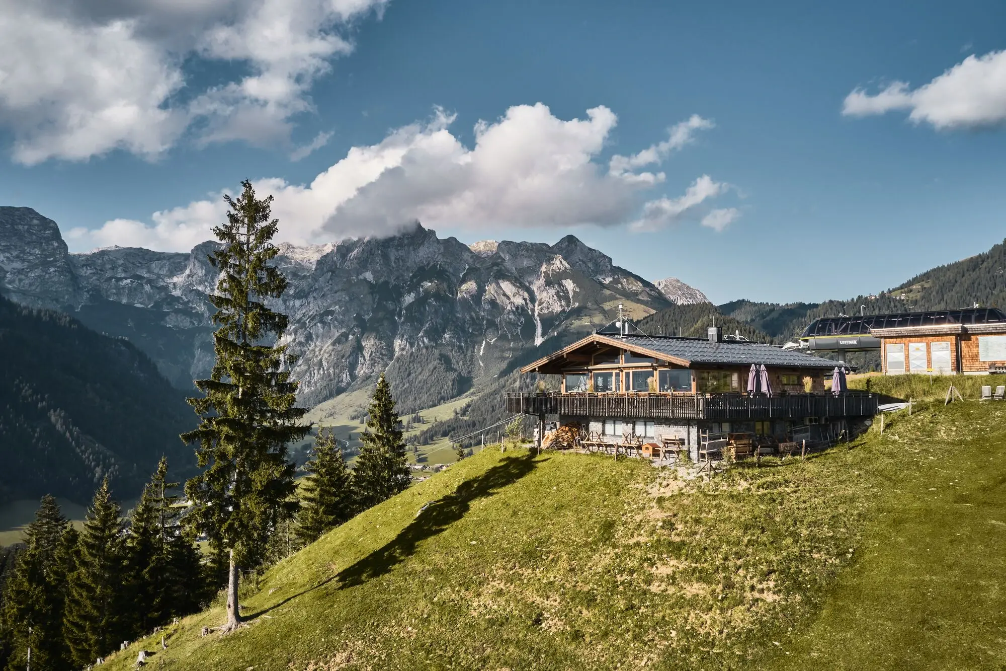 Ein grünes Tal in den bayrischen Alpen, durch das eine Straße mit eijn paar Häusern führt. 