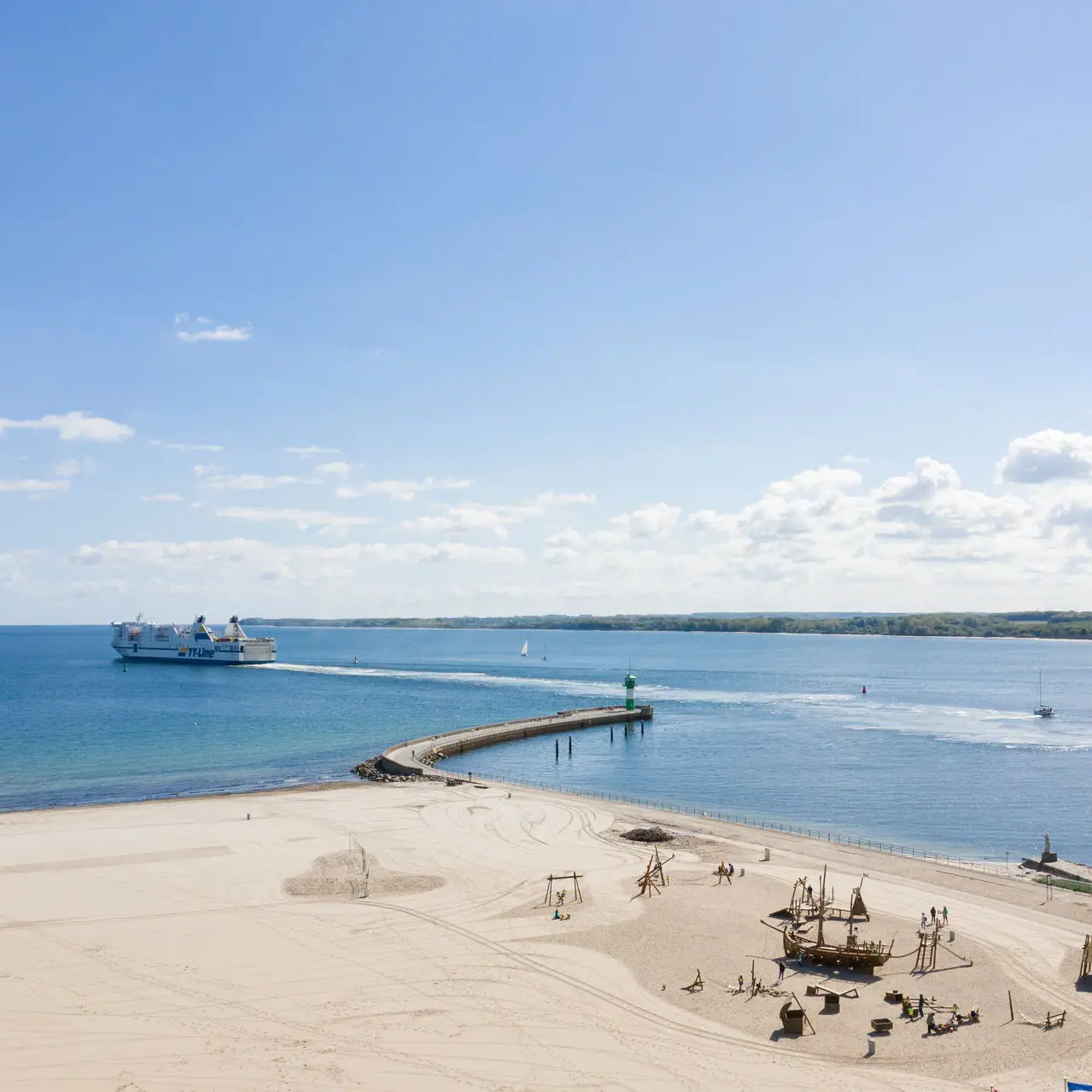 Kurstrand Travemünde Ein Strand mit einem Steg und einem Boot im Wasser.