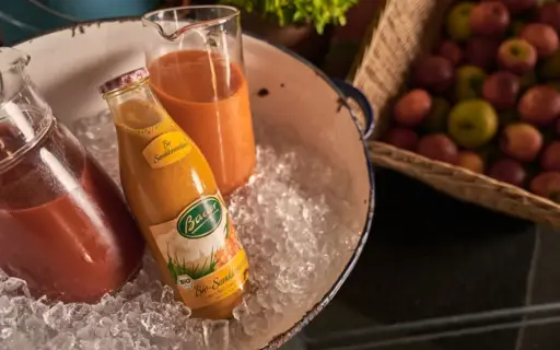 A large tub of ice containing a bottle and two carafes of juice. 