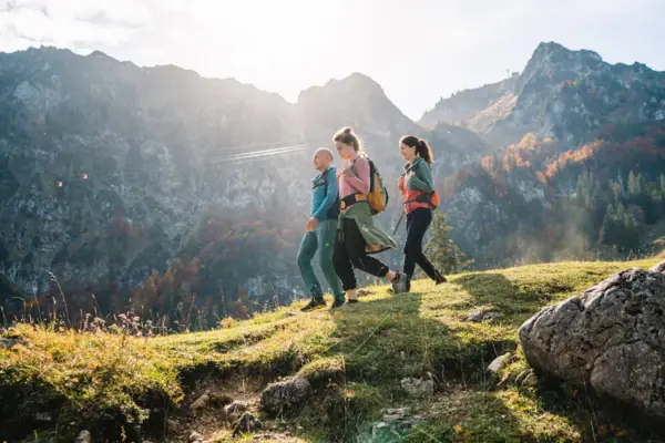 Eine Gruppe von Menschen wandert in Ruhpolding auf einem Hügel mit Bergen im Hintergrund.