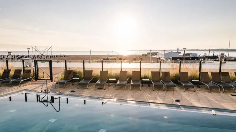 Wellness mit Aussicht in Travemünde  Ein Pool mit Stühlen und einem Strand im Hintergrund.