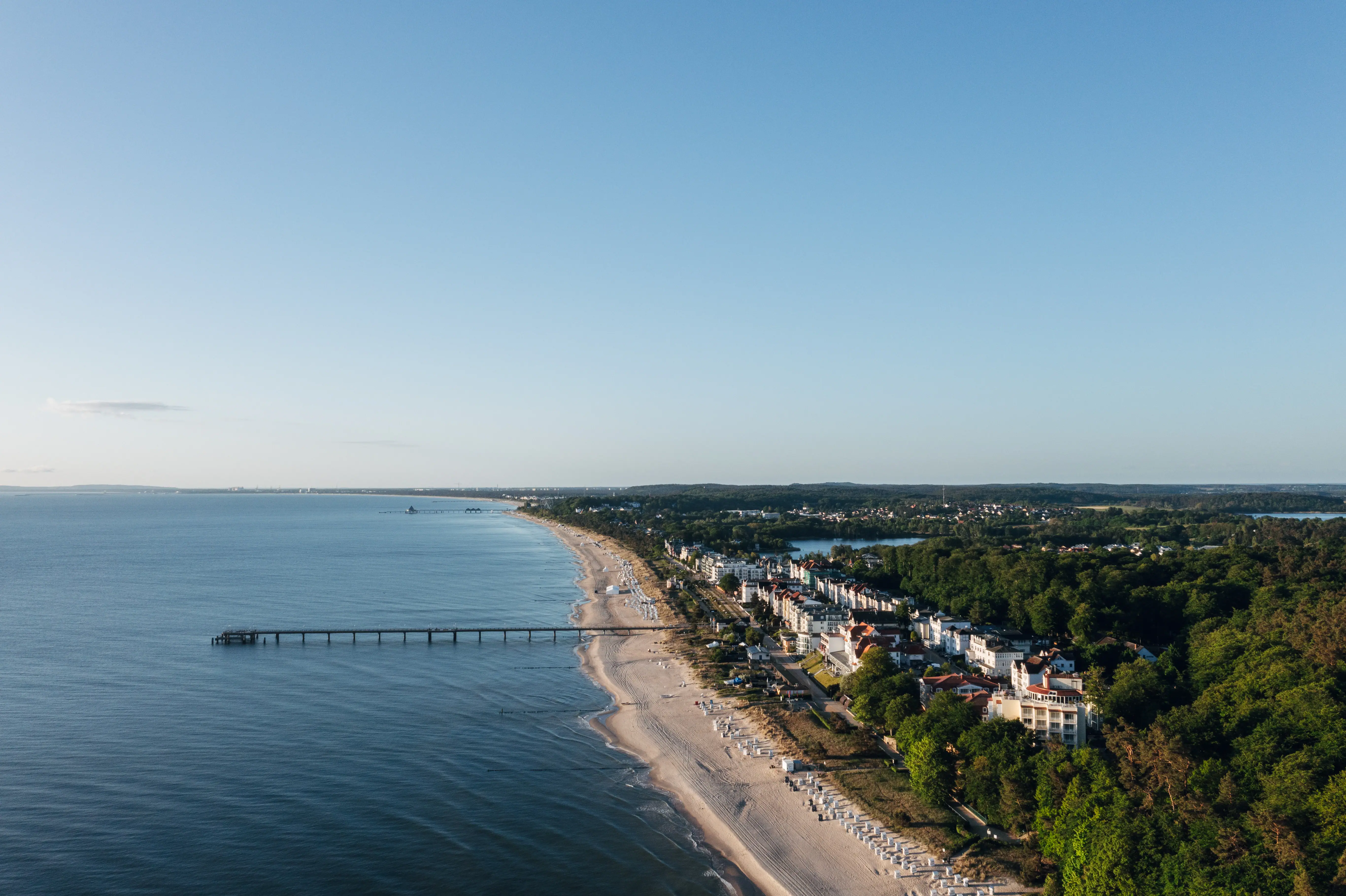 Strand mit einem Pier und Gebäuden im Hintergrund.