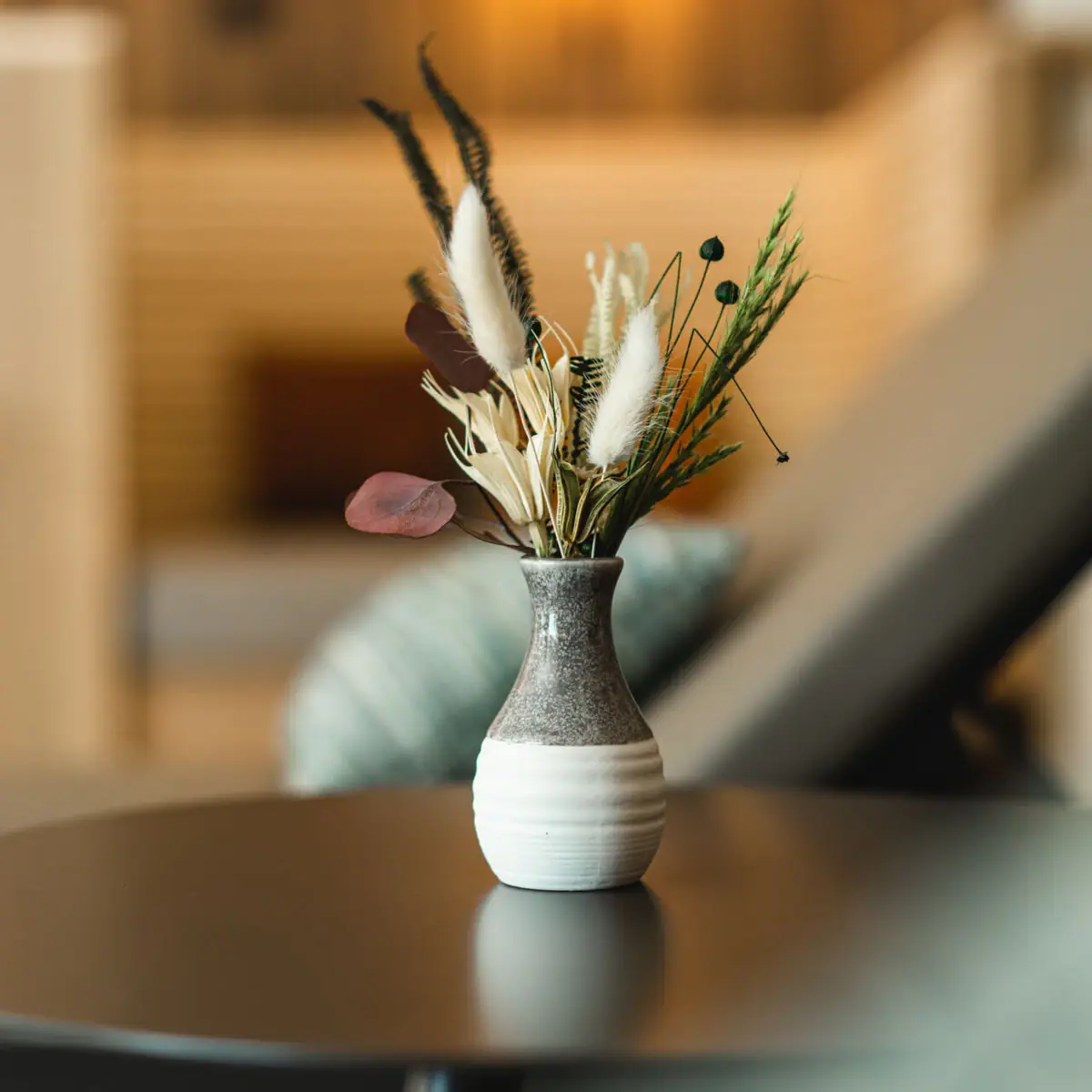 Eine Vase mit getrockneten Blumen auf einem Tisch.