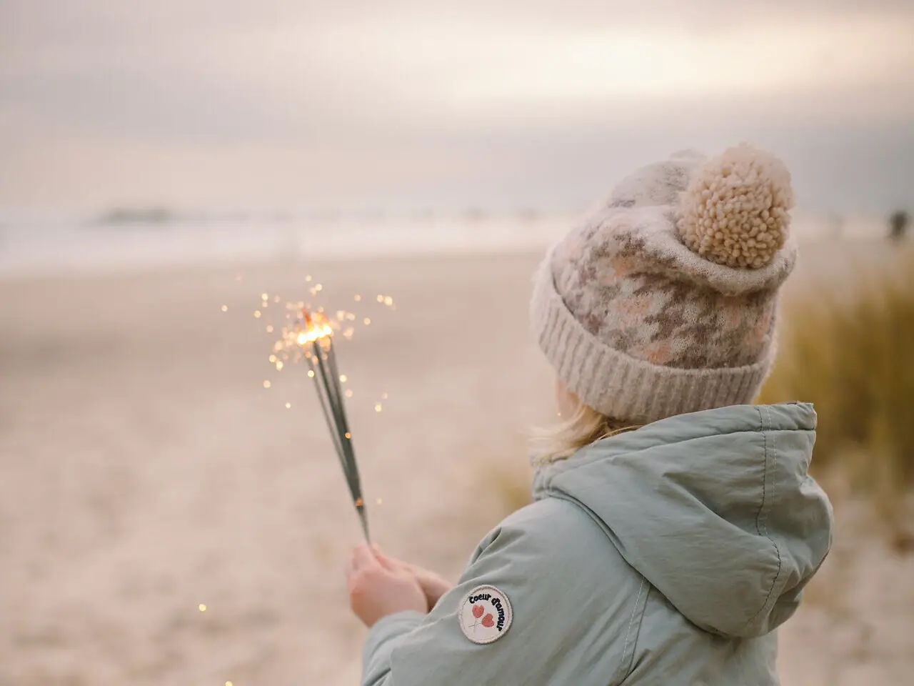 Ein Mädchen hält Wunderkerzen am Strand.