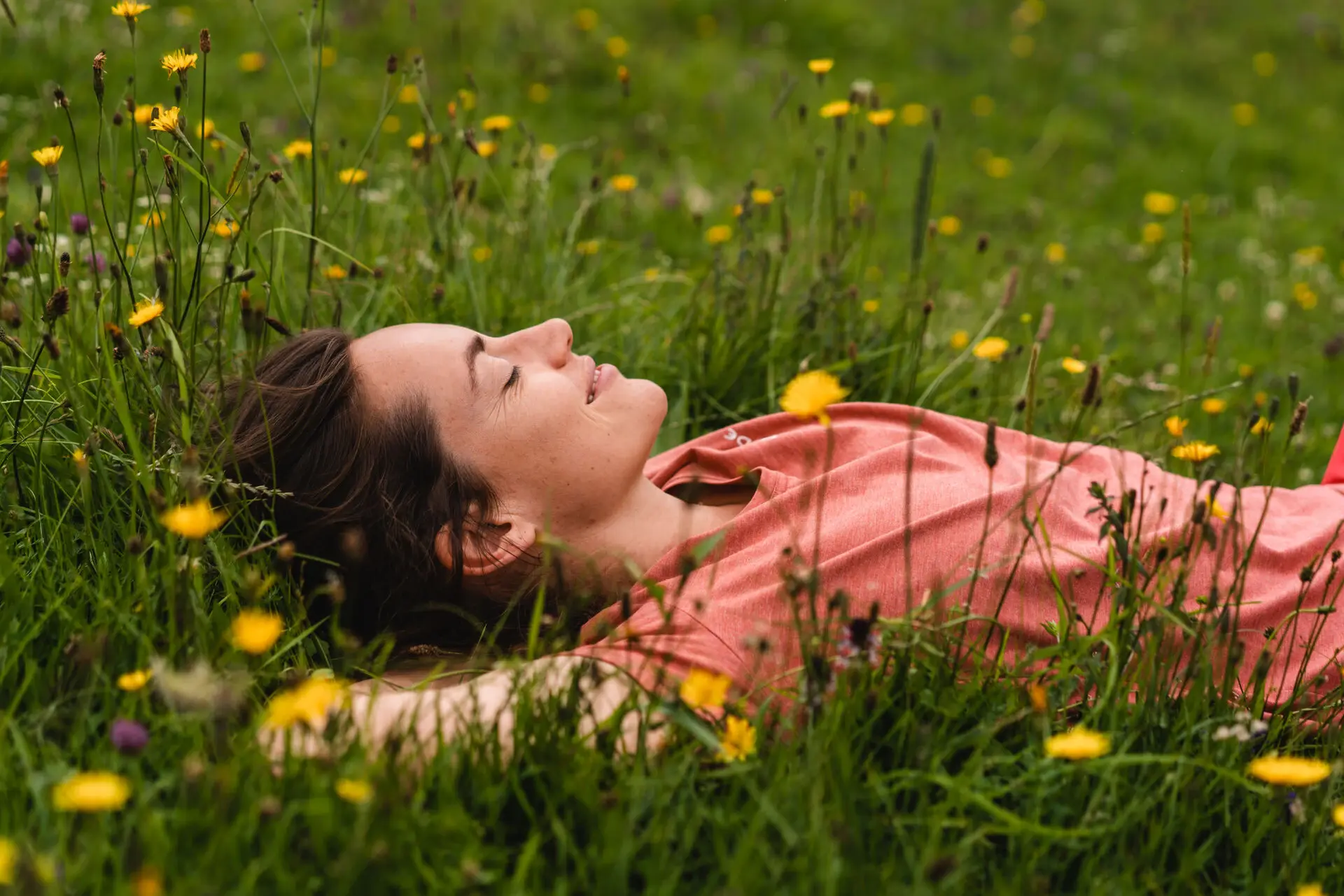 Eine Frau liegt mit geschlossenen Augen im Gras.