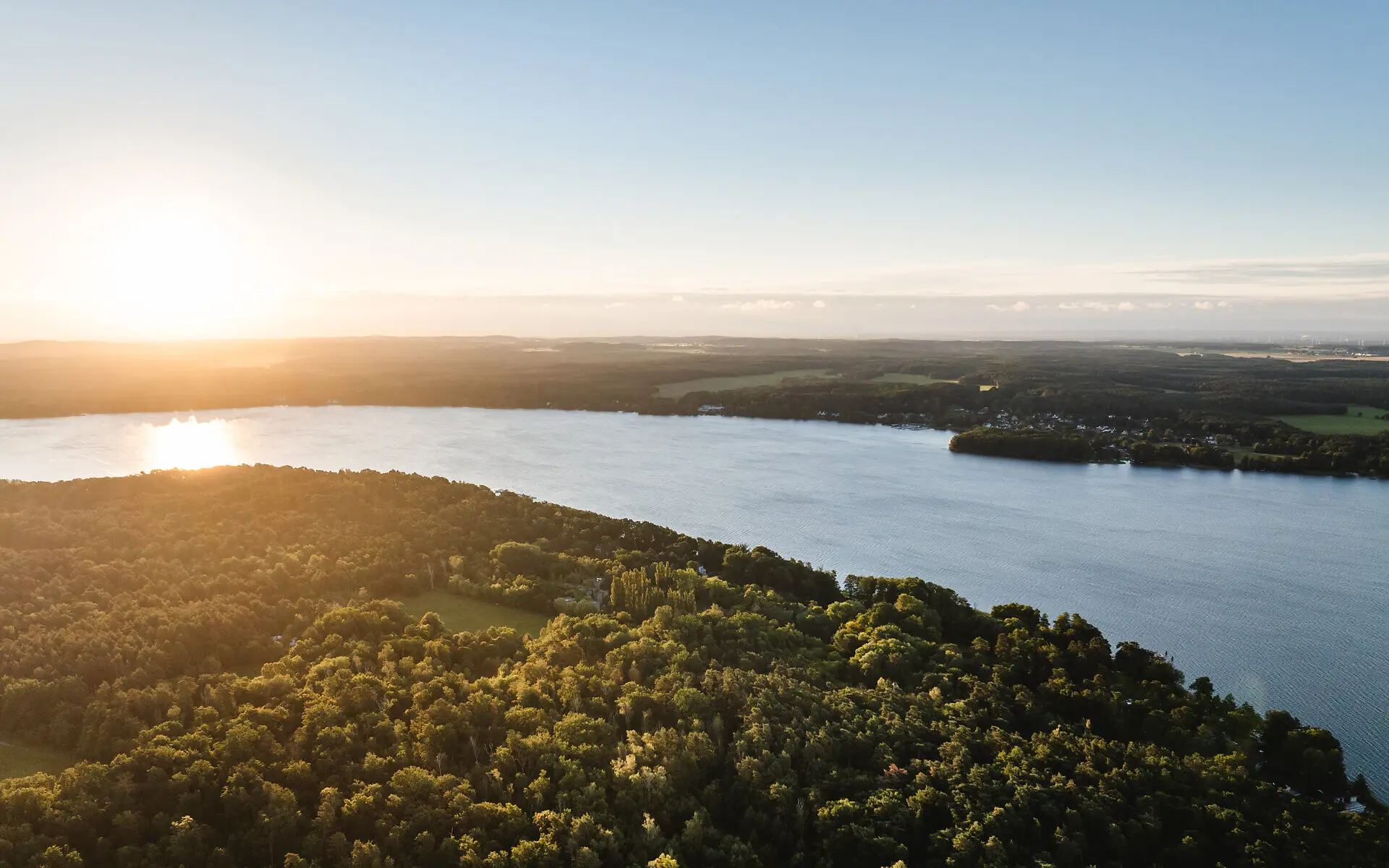 Scharmützelsee Ein Gewässer mit Bäumen und einer Stadt in der Ferne.