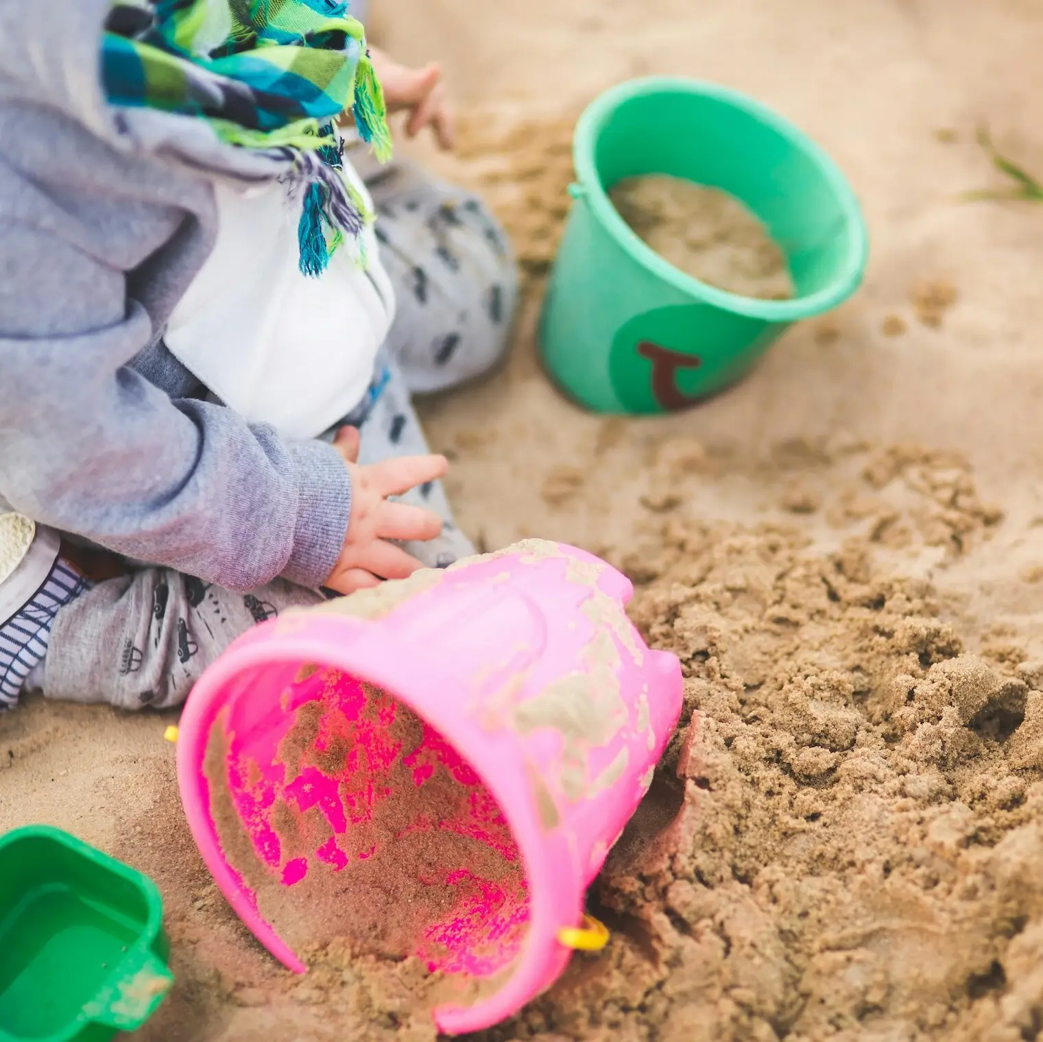 A child plays with a bucket in the sand.