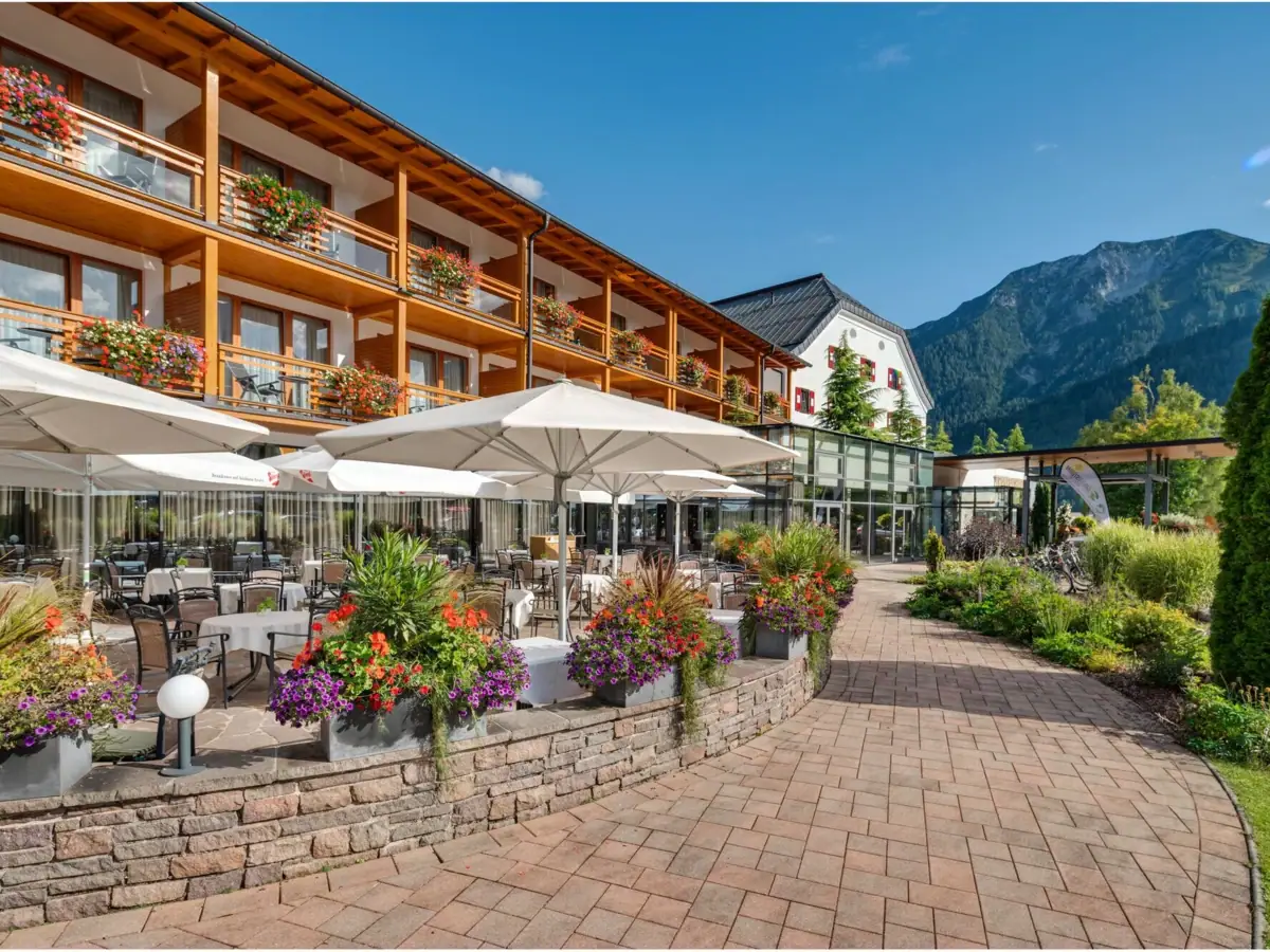 aja Fürstenhaus am Achensee Ein Gebäude mit Terrasse und Sonnenschirmen.