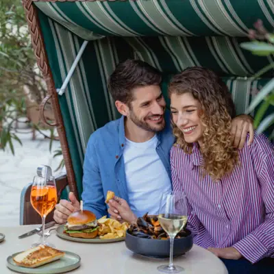 Bistro & Bar Patio Ein Mann und eine Frau sitzen an einem Tisch mit Essen und Getränken.