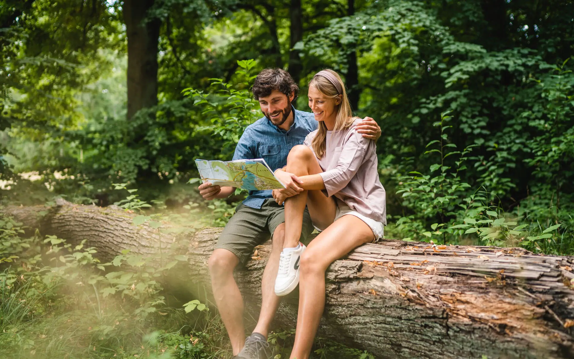 Paar sitzt auf einem Baumstamm in der Natur