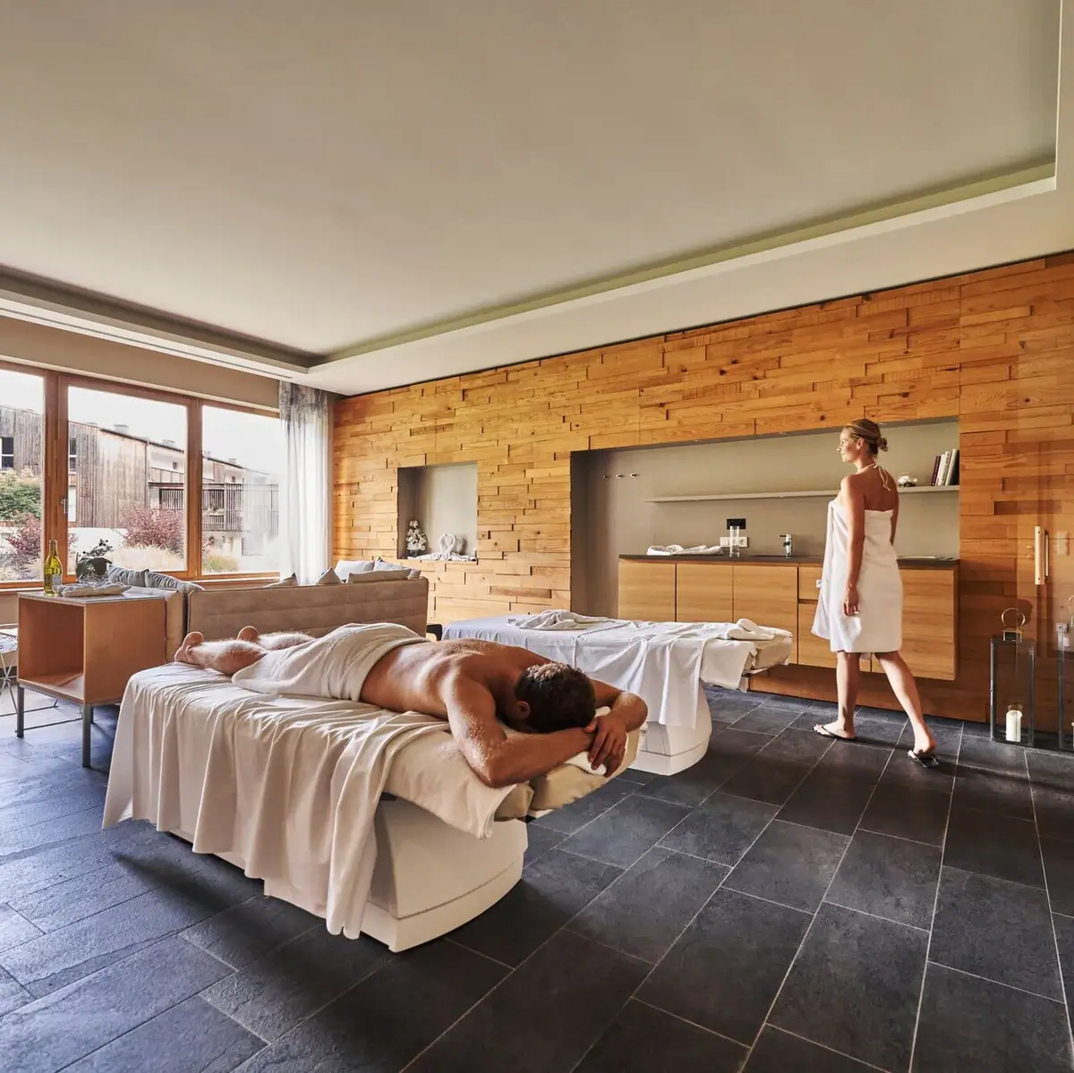 Massage Ein Mann liegt auf einem Bett, während eine Frau hinter ihm steht.