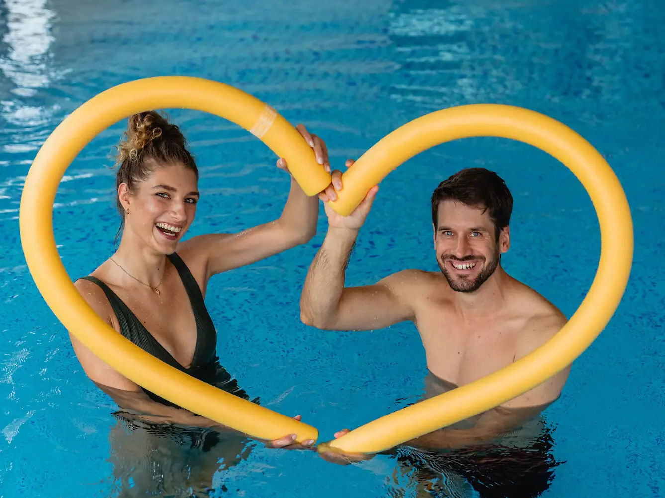 Ein Mann und eine Frau halten ein gelbes herzförmiges Rohr.