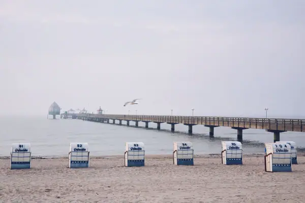 Ein Strand mit Stühlen und einem Pier.
