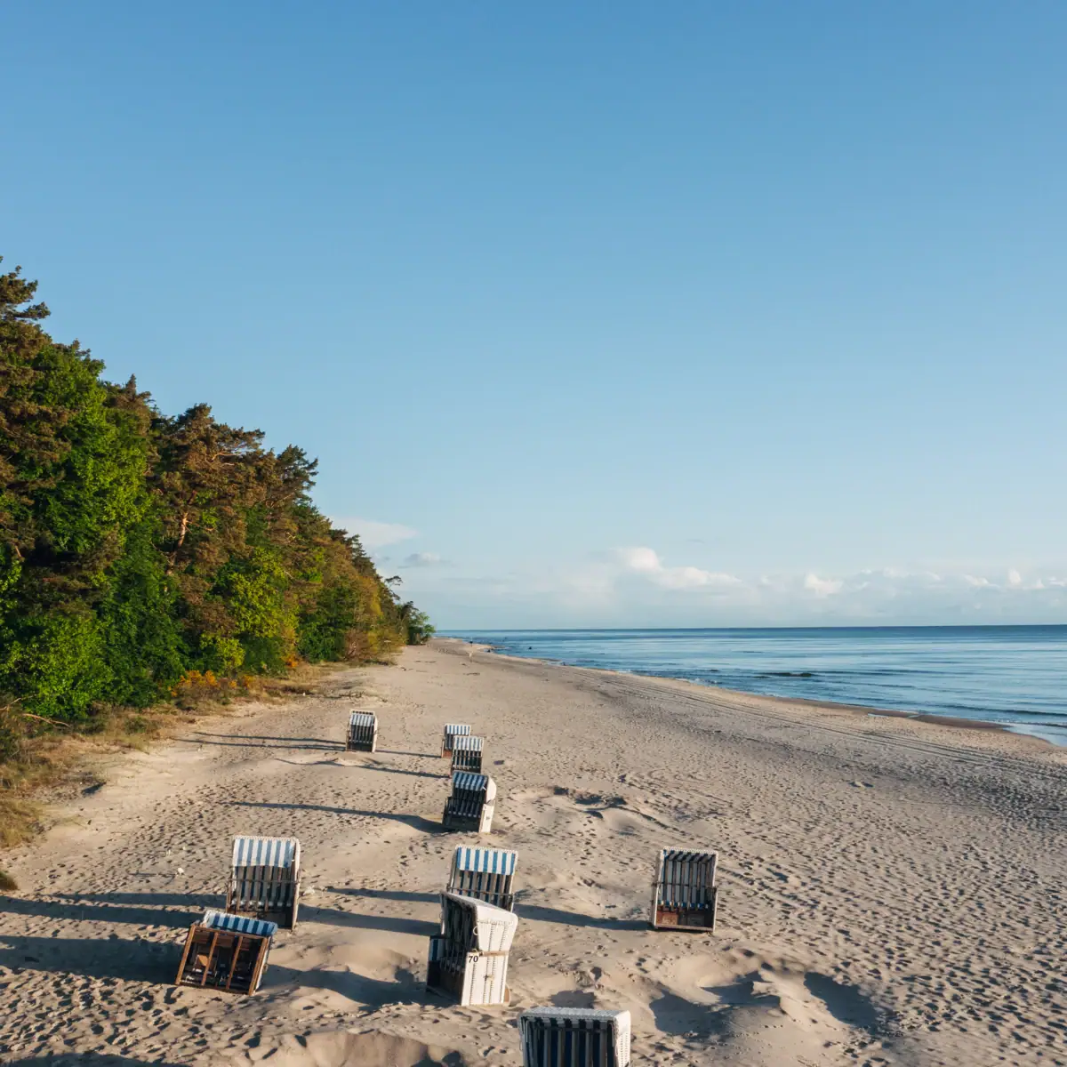 Stühle am Strand mit Blick auf das Wasser und den Himmel.