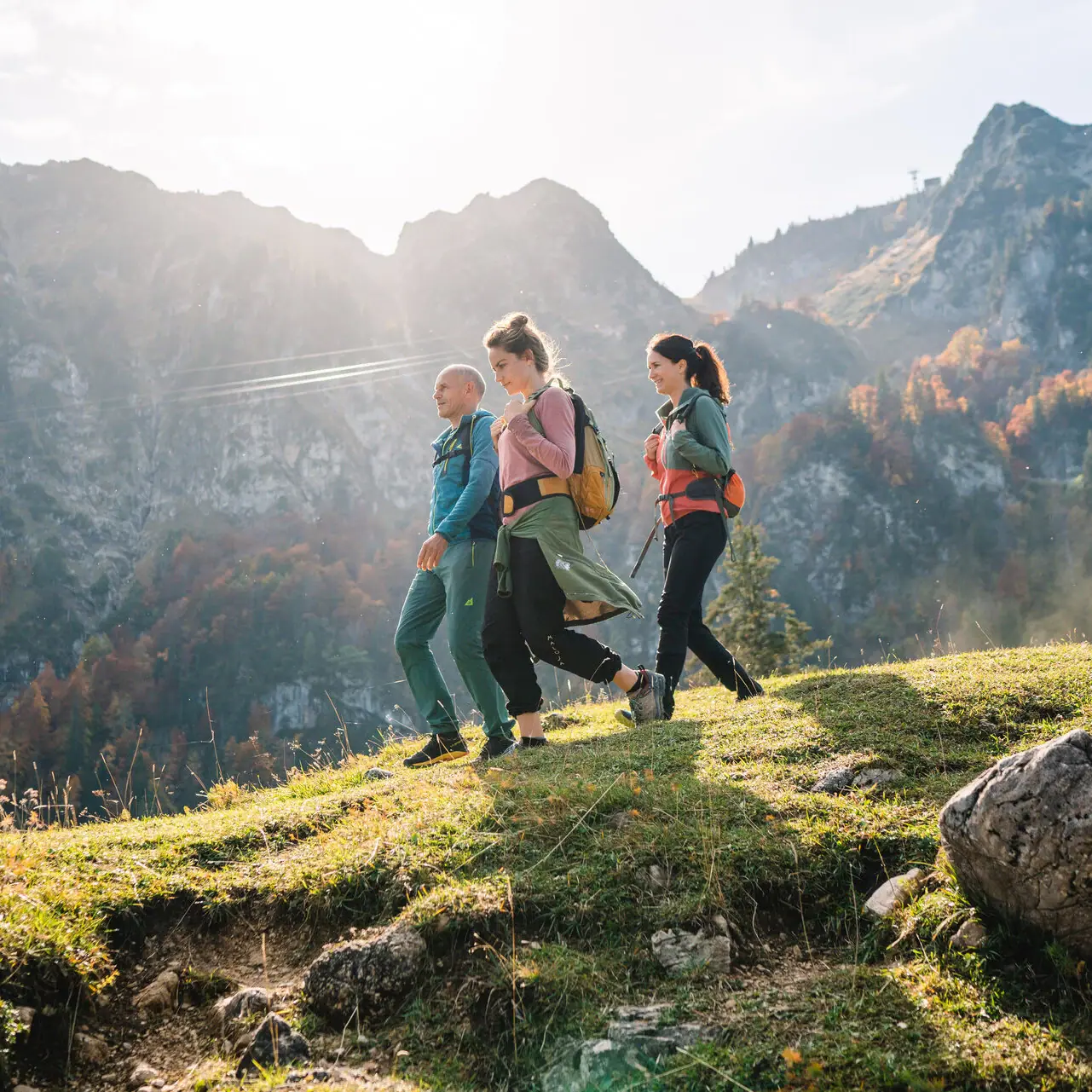 Eine Gruppe von Menschen wandert auf einem Hügel mit Bergen im Hintergrund in Ruhpolding.