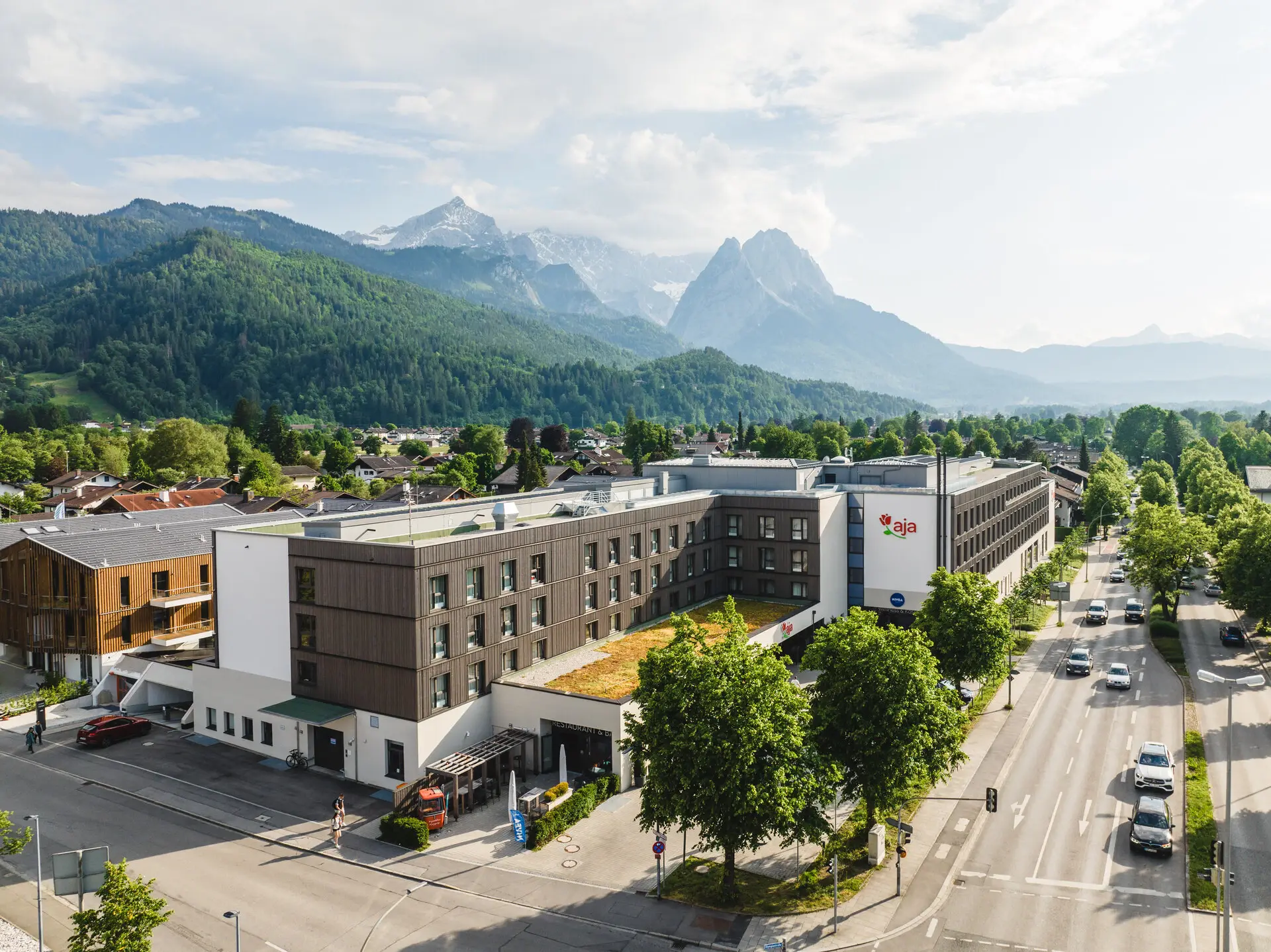 Das aja Garmisch-Partenkirchen von außen fotografiert mit Bergen im Hintergrund.