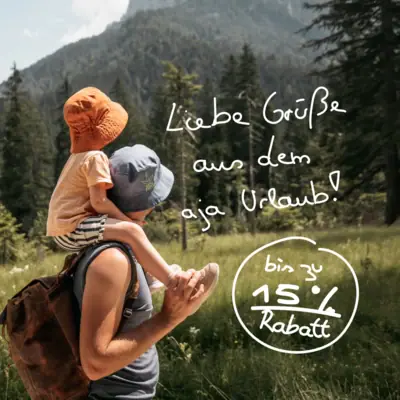 Ein Mann trägt ein Kind auf seinen Schultern im Freien.