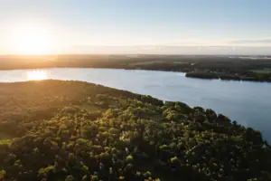 Scharmützelsee Ein Gewässer mit Bäumen und einer Stadt in der Ferne.