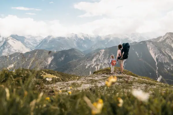 Eine Familien auf einer Wanderung in Bayern mit Bergen im Hintergrund.