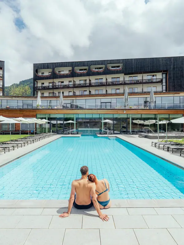Außenpool Ein Mann und eine Frau sitzen am Rand eines Pools.