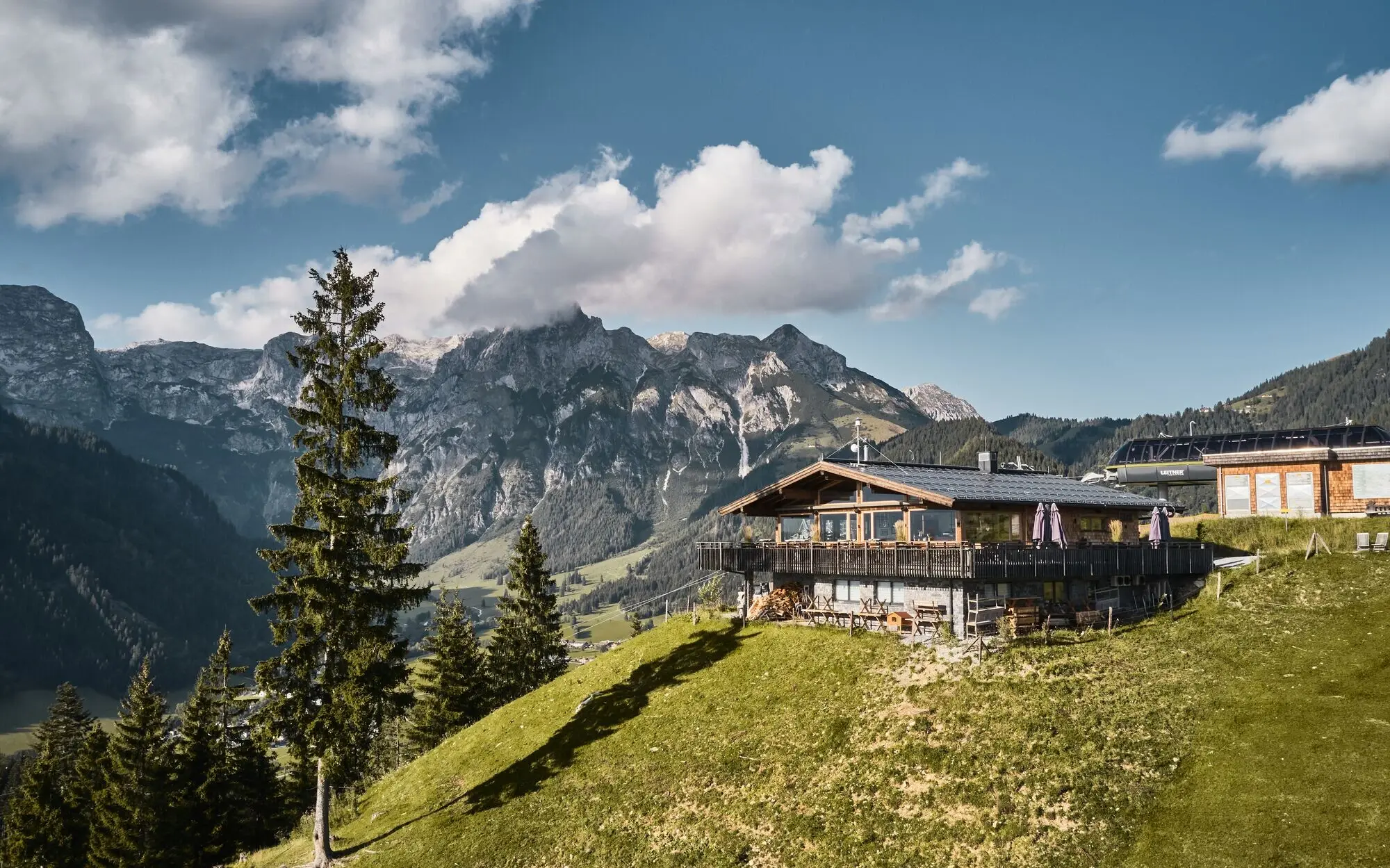 Hut on a hill with mountain landscape in the background.