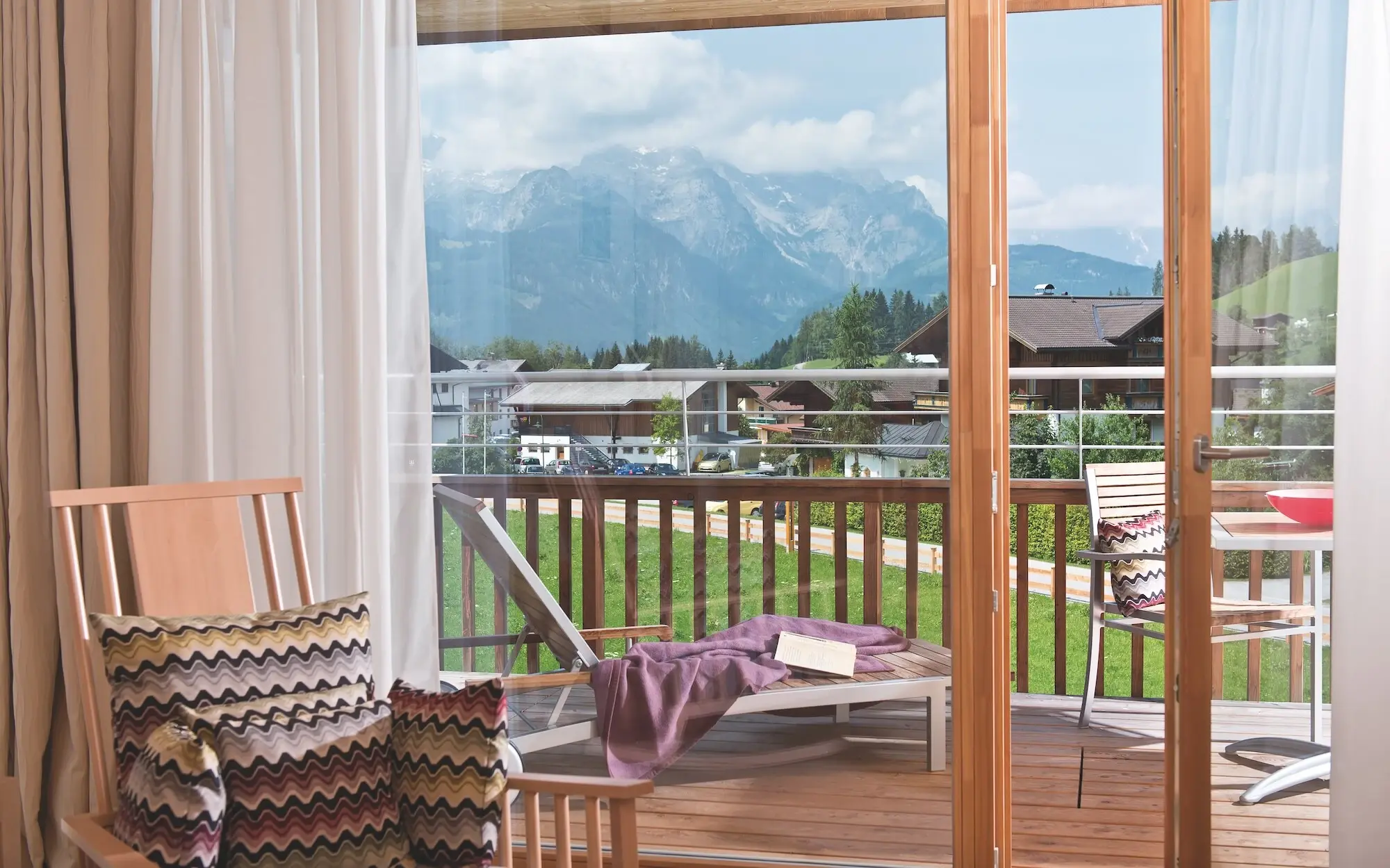 Balkon mit Blick auf Berge und Bäume, ausgestattet mit Tisch und Stühlen.