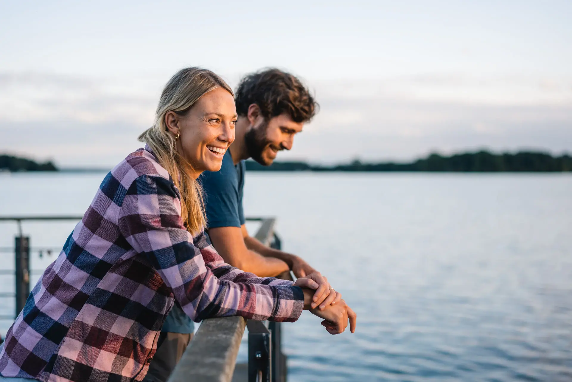 Paar am See Ein Mann und eine Frau lehnen an einem Geländer am Wasser.