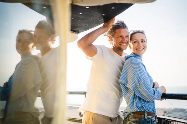 Warnemünde Paar Ein Mann und eine Frau stehen lächelnd auf einem Boot.