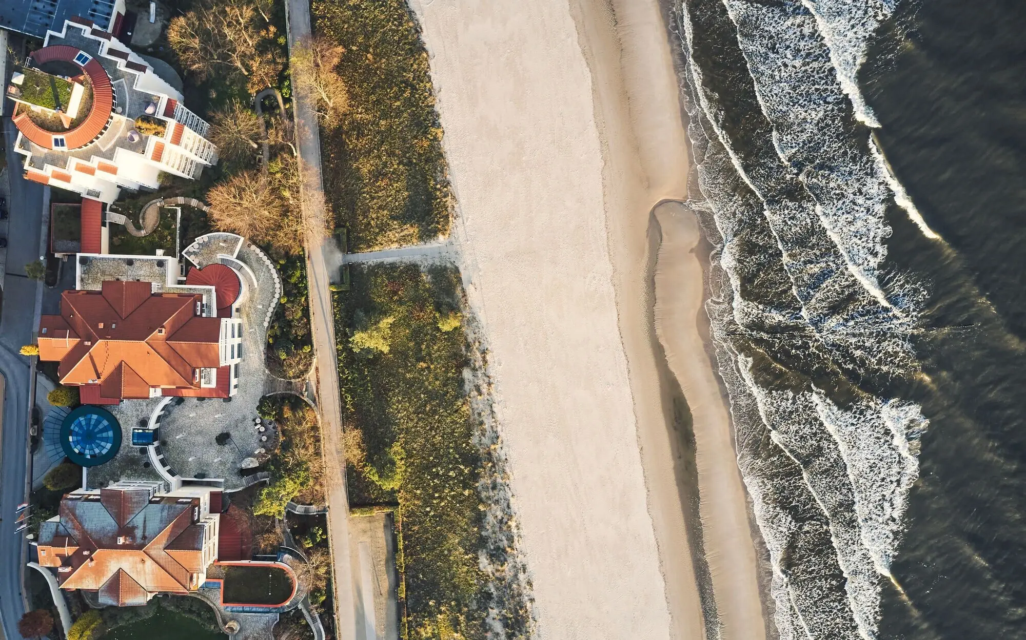 Strand mit Häusern und Wellen