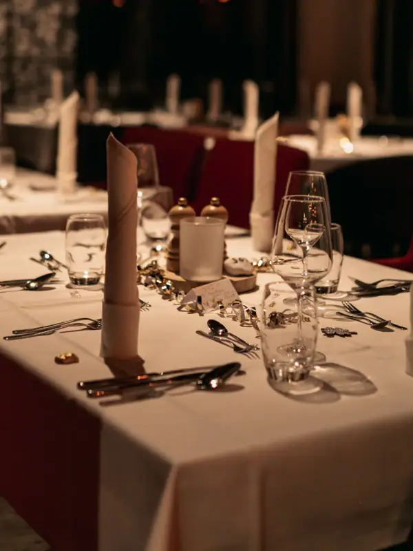 Ein Tisch, gedeckt für eine Dinnerparty, mit Kerzen und Tischgedeck.