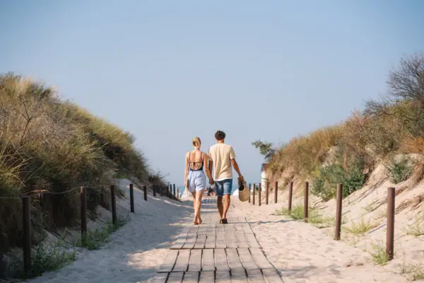 Strandaufgang Warnemünde Eine Frau und ein Mann gehen Hand in Hand zum Strandaufgang in Warnemünde.