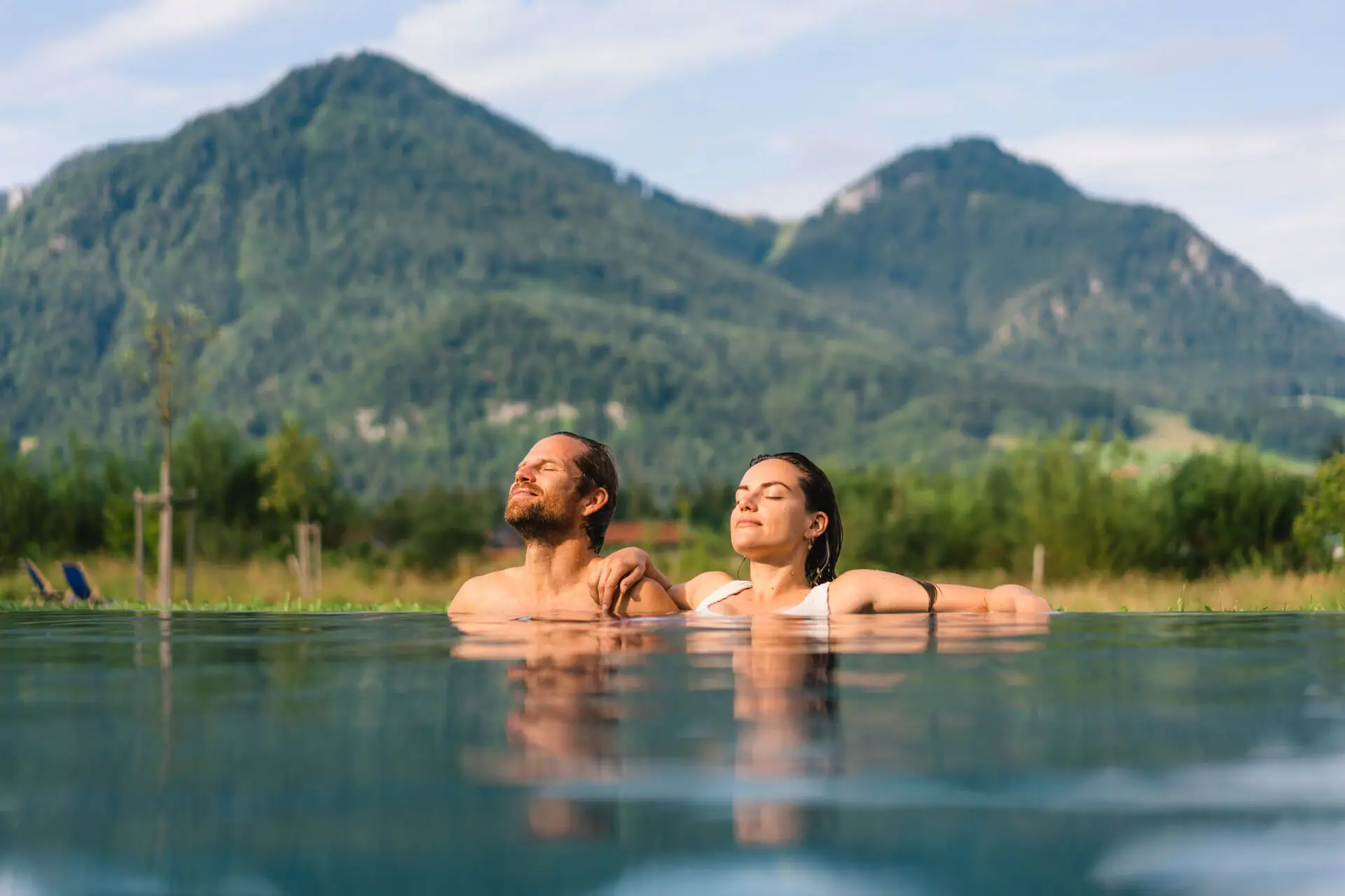 Ein Mann und eine Frau in einem Pool mit Bergen im Hintergrund.