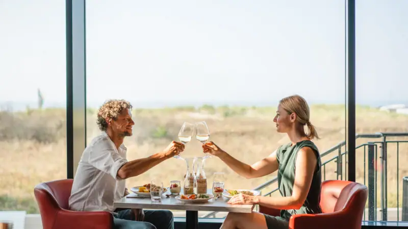 Restaurant im aja Warnemünde Ein Mann und eine Frau sitzen an einem Tisch mit Weingläsern.