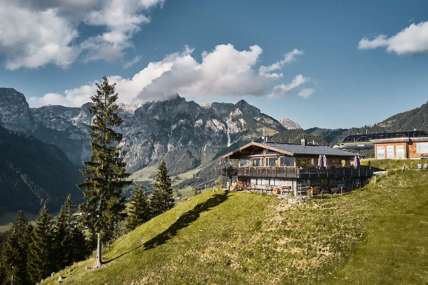 Hütte auf einem Hügel mit Berglandschaft im Hintergrund.