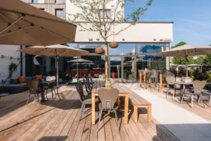 Eine Terrasse mit Tischen und Sonnenschirmen.