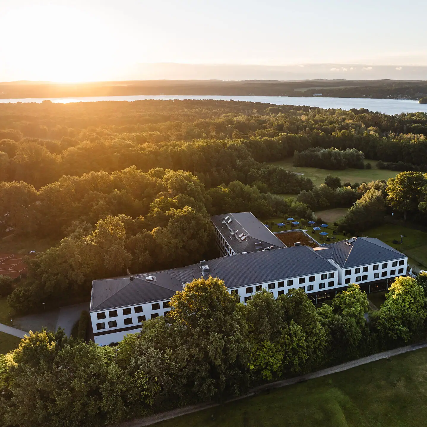 aja Bad Saarow Ein Gebäude umgeben von Bäumen und einem Gewässer.