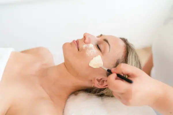 Eine Frau liegt mit einem Pinsel auf ihrem Gesicht.