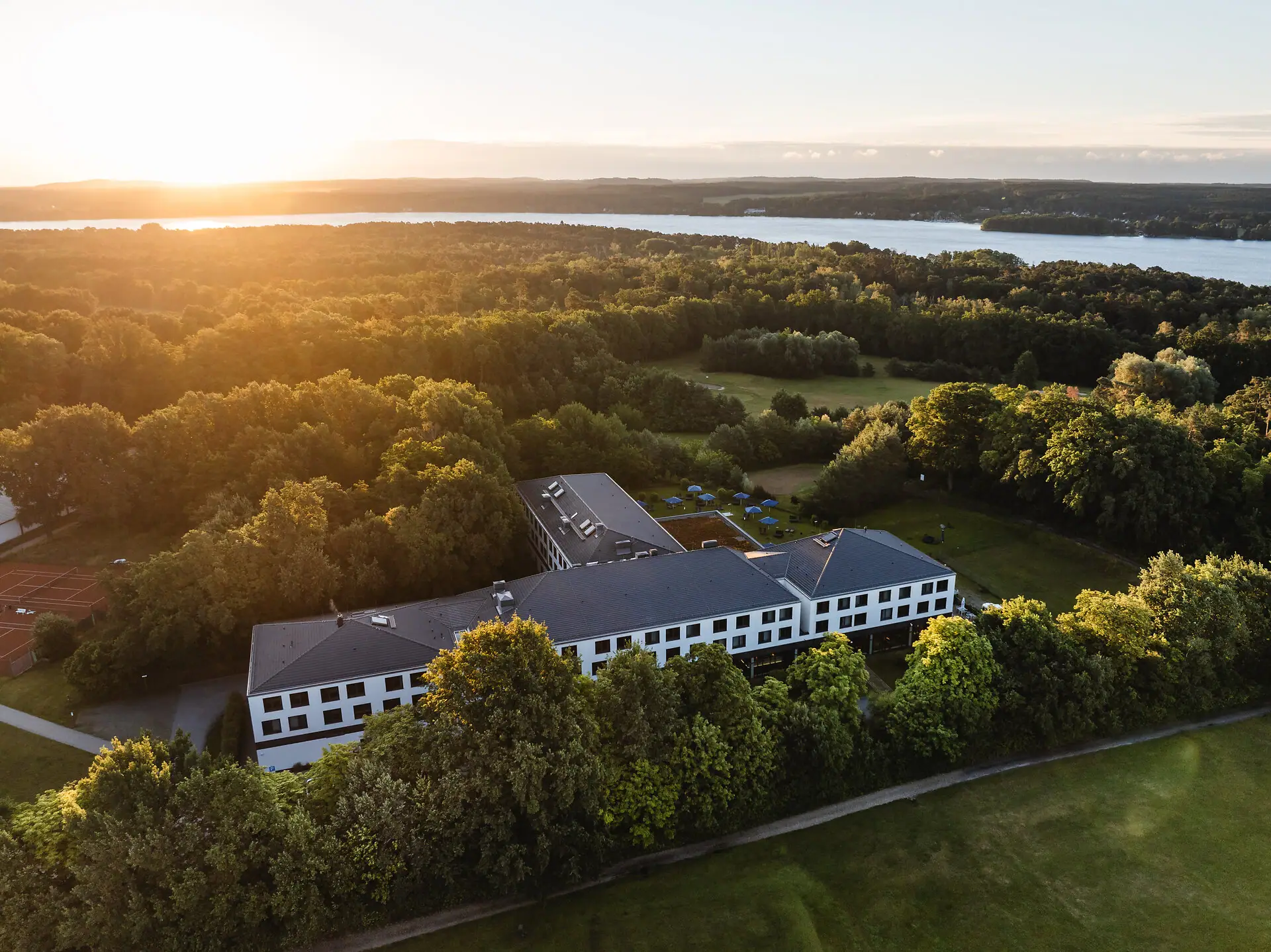 aja Bad Saarow Ein Gebäude umgeben von Bäumen und einem Gewässer.