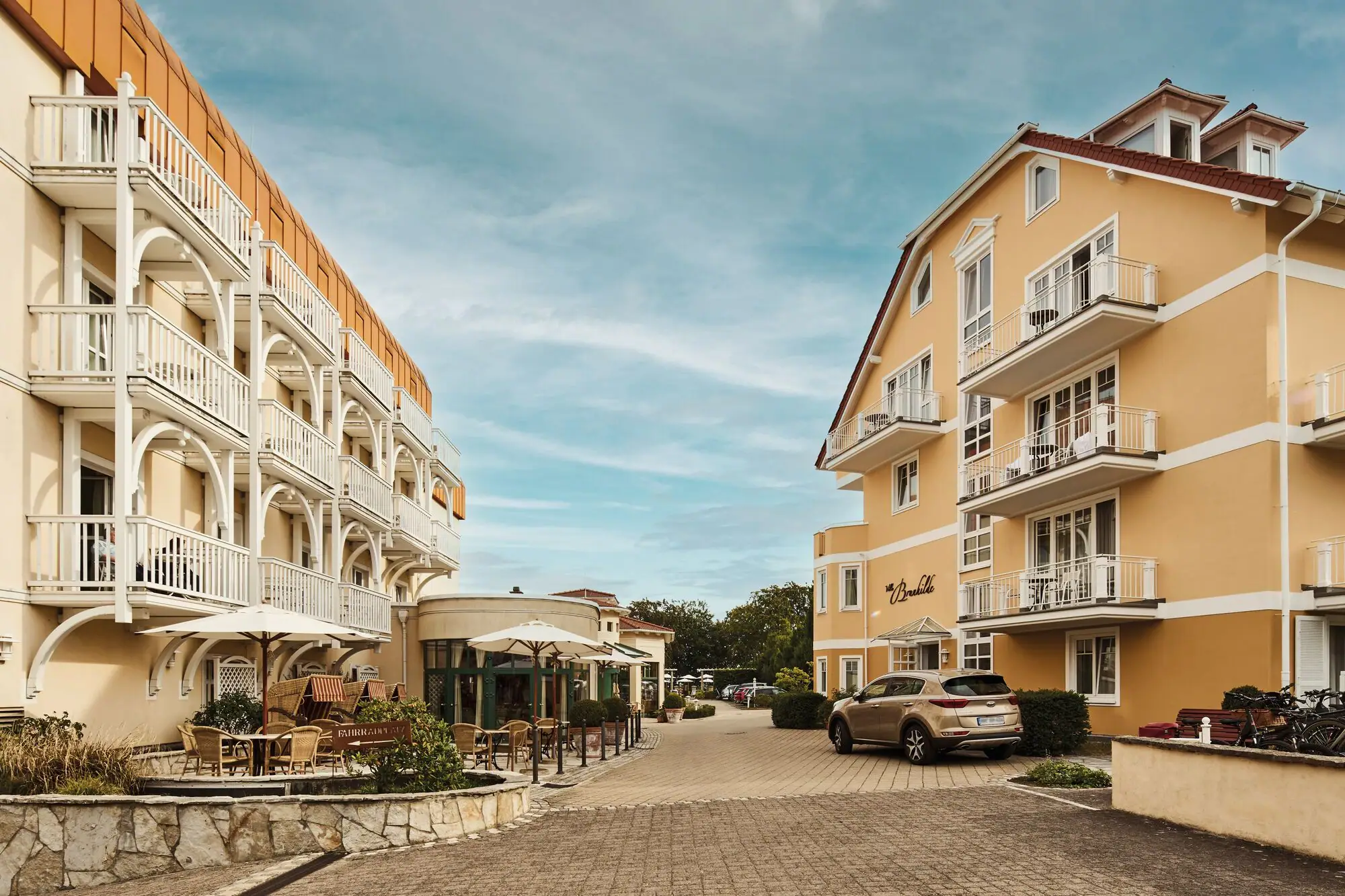 Straße mit Gebäuden und geparkten Autos im Freien bei bewölktem Himmel.