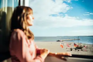 Doppelzimmer Eine Frau blickt aus einem Fenster auf einen Strand.