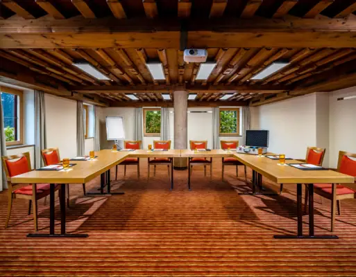 Tagungsraum Tagungsbereich mit Tischen in U-Form, Stühlen und Fenstern.