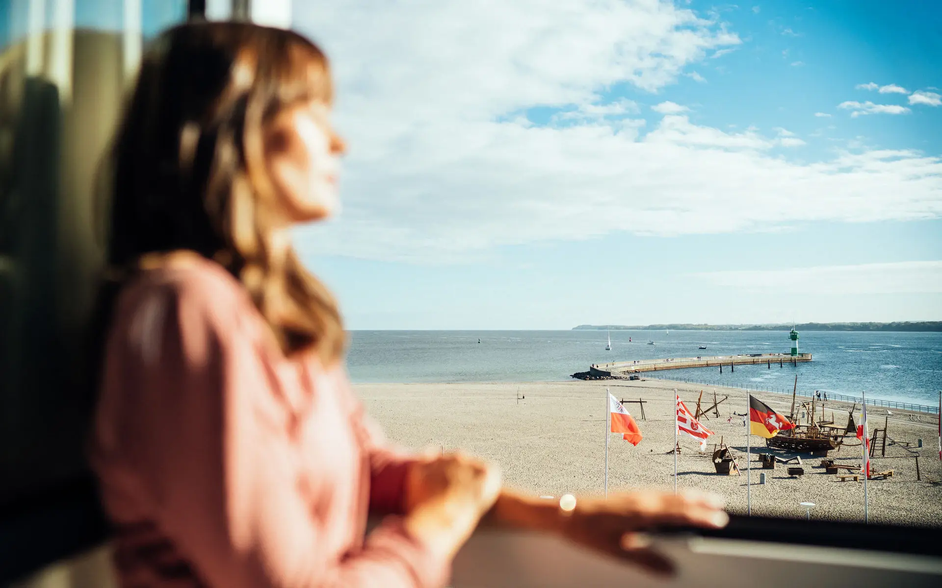Eine Frau steht auf einem Balkon und blickt auf das Meer