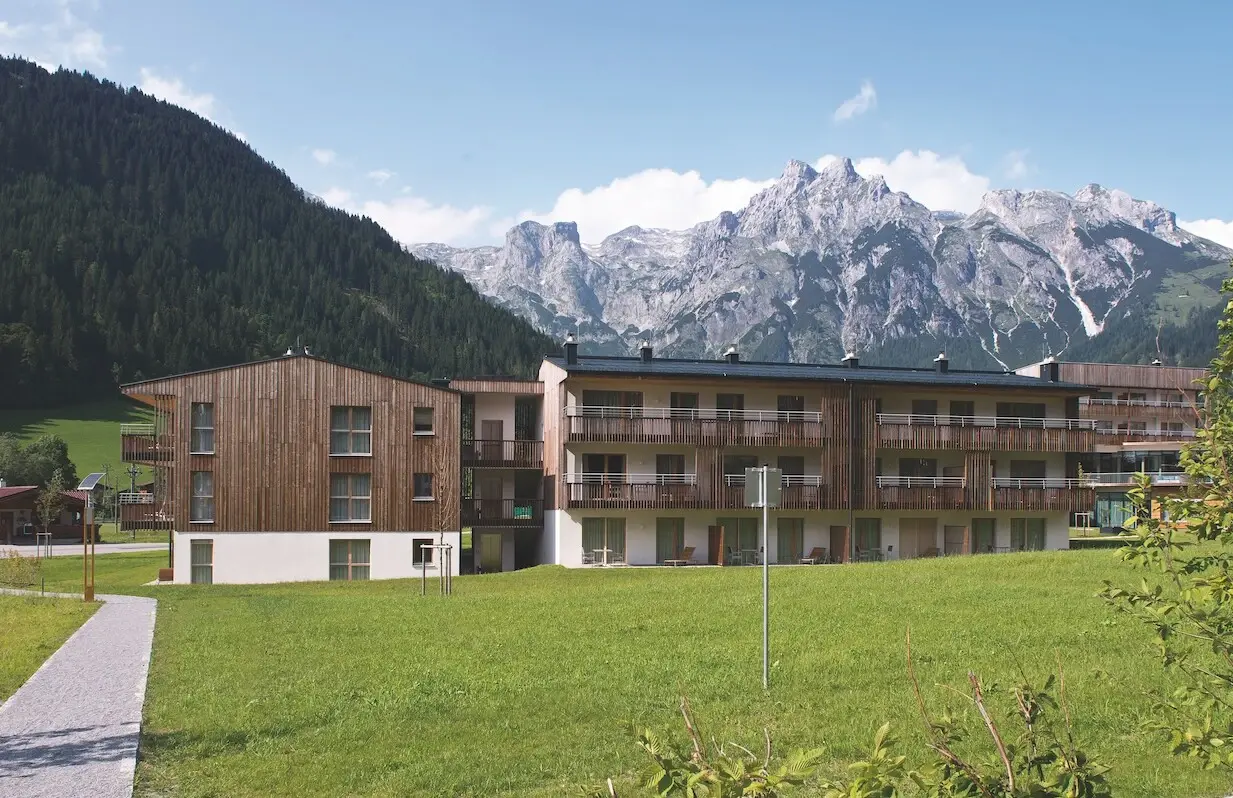 A building with a lawn and mountain backdrop.